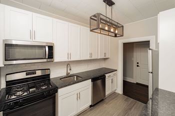 A kitchen with white cabinets and a black stove and a microwave